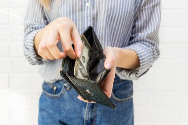 Genç bir kadının açık bir cüzdanın son banknotunu çekerken yakın plan fotoğrafı. Para yok, iflas, mali sorunlar, kriz, işsizlik, harcama konsepti için kaynak yetersizliği.