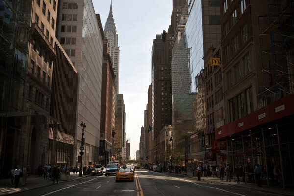New York, USA - May 7, 2013 : Typical street in New York with a taxi and some cars coming and buildings all around. Behind the scene, the Chrysler building on the left with its steel structure high in Midtown Manhattan, New York, USA
