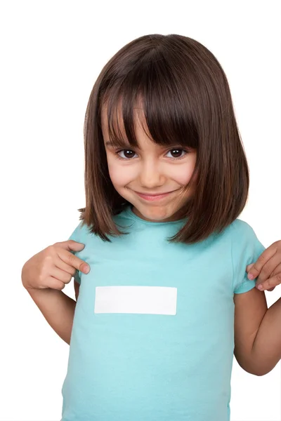 Little girl pointing to white sticker in her shirt — Stock Photo, Image