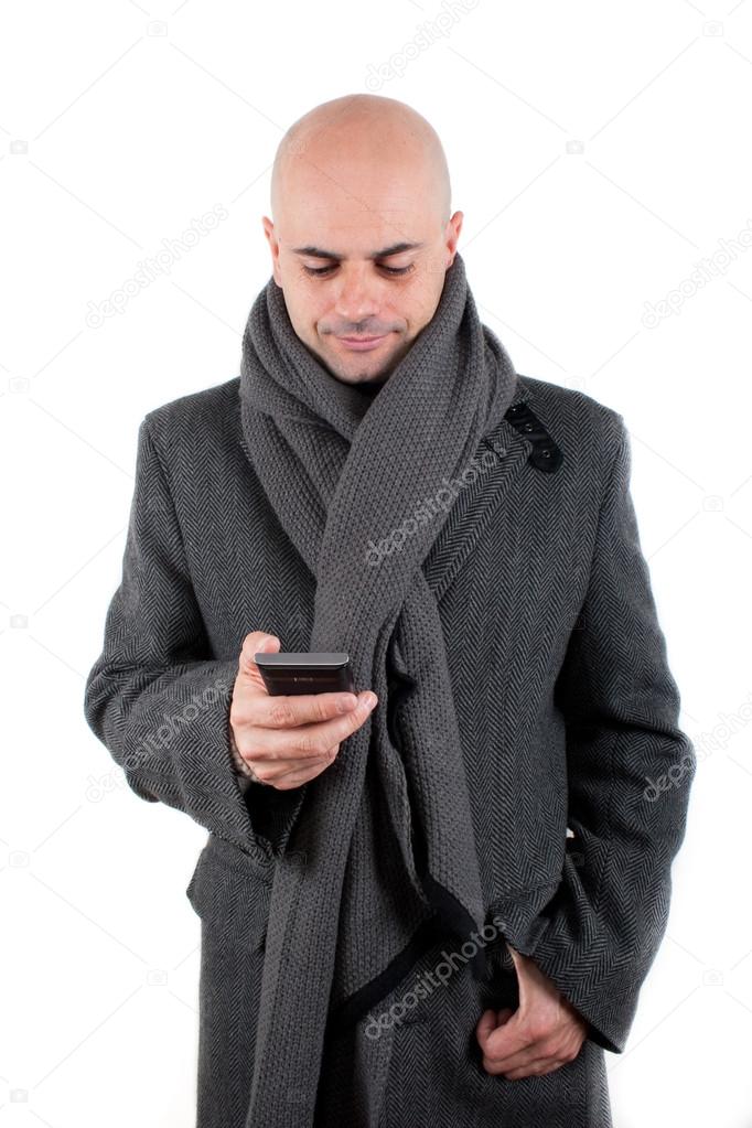 Man with coat and scarf using his smartphone.