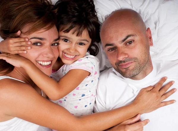 Familia abrazada en la cama — Foto de Stock