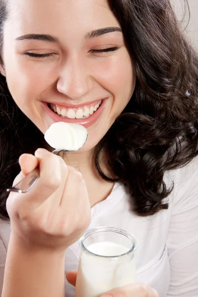 Mujer feliz riendo con los ojos cerrados mientras come un yogur — Foto de Stock