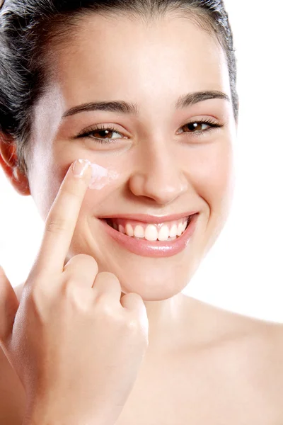 Beautiful girl applying moisturizing cream on her cheek — Stockfoto