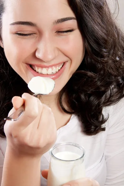 Donna felice che ride a occhi chiusi mentre mangia uno yogurt Immagine Stock