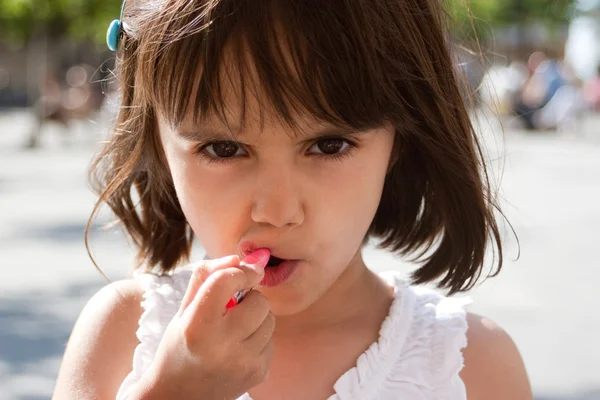 Liten flicka att sätta på läppstift — Stockfoto