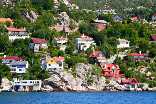 Domy a chaty na břehu a kopce fjordu bergen. — Stock fotografie