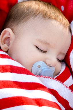 kırmızı bir battaniyeye sarılmış uyuyan bebek