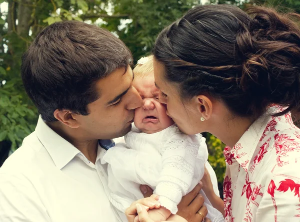Родители целуют плачущего ребенка — стоковое фото