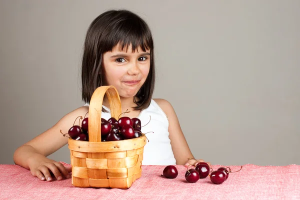 Liten flicka leende medan man äter körsbär — Stockfoto