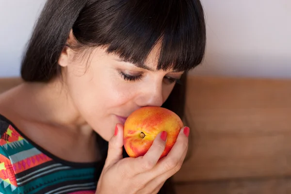 Young woman smelling a nectarine — Stock Photo, Image
