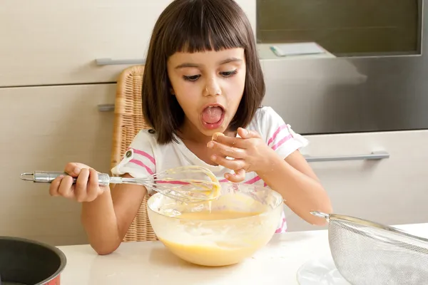 Niña feliz degustando la mezcla para cocinar un pastel — Foto de Stock