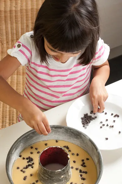 Glückliches kleines Mädchen beim Kochen eines Schokoladenchips Kuchen — Stockfoto