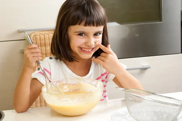 Linda y feliz niña cocinando un pastel — Foto de Stock