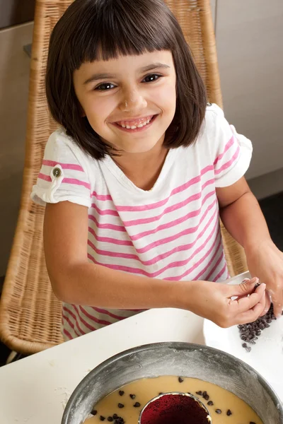 Glückliches kleines Mädchen beim Kochen eines Schokoladenchips Kuchen — Stockfoto