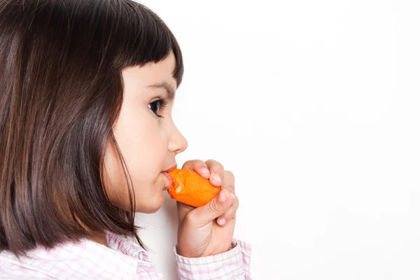 Vacker liten flicka äter en morot — Stockfoto