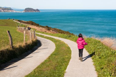 Little girl walking along a path by the sea clipart