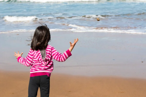 Mädchen wirft Felsbrocken ins Meer — Stockfoto