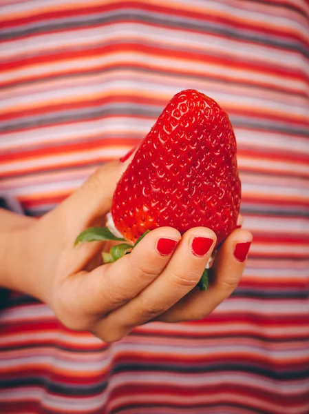 Child hand with big strawberry