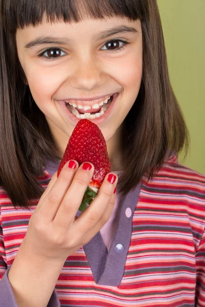 Happy little girl eating a big strawberry