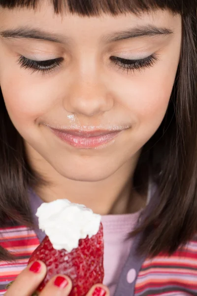 Liten flicka äter jordgubbar med grädde — Stockfoto