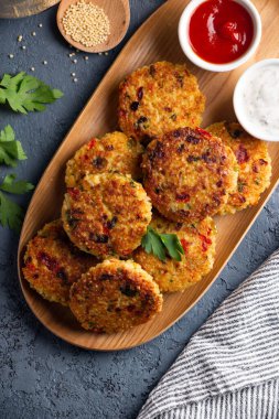 Domates ve yoğurt sosuyla servis edilen glütensiz vejetaryen darı ve sebze burgeri. Üst görünüm
