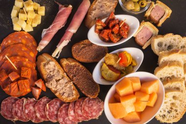 Kahverengi arka planda dilimlenmiş sosis ve peynir. İtalyan antipasti şarap aperatifleri. Peynir, Akdeniz zeytinleri kavunlu jambon, ekmek çubukları, salam..