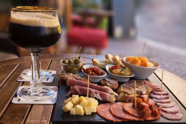 Villefranche-sur-Mer, Fransa, Eylül 2021. Dışarıdaki ahşap masa, yanında da bira karşıtı aperatifler. Dilimlenmiş? Sosis, peynir Akdeniz zeytinleri, kavunlu jambon, ekmek çubukları.