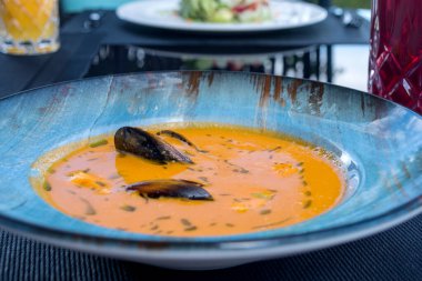 Lezzetli deniz ürünleri domatesli balık çorbası. Masada karides, midye ve balık var. Balık lokantasında nefis romantik bir akşam yemeği. Bir tabak geleneksel Fransız mutfağı..