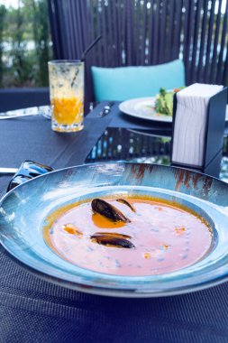Lezzetli deniz ürünleri domatesli balık çorbası. Masada karides, midye ve balık var. Balık lokantasında nefis romantik bir akşam yemeği. Bir tabak geleneksel Fransız mutfağı..