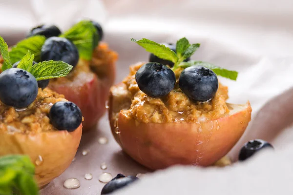 Blueberries on a baked apple in an oven with syrup, cinnamon and mint on parchment paper. Dietary eating. Autumn dish. Traditions of Ukrainian and German cuisine.