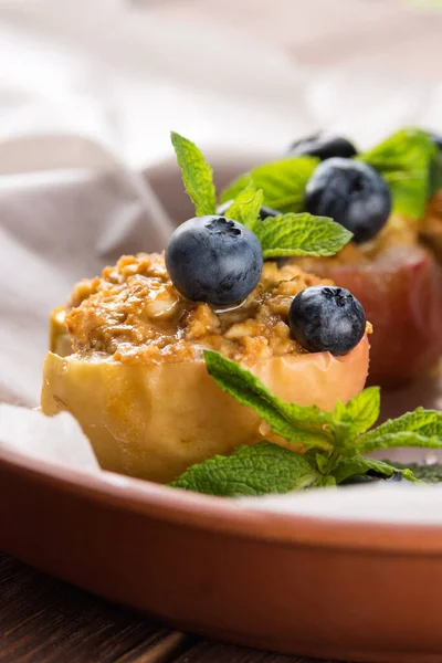 Blueberries on a baked apple in an oven with syrup, cinnamon and mint on parchment paper. Dietary eating. Autumn dish. Traditions of Ukrainian and German cuisine.