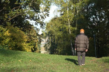 Moskova şehri, 2021 sonbaharı, Suvorovsky Park yaya geçidi, sırtında siyah bir ceketle yürüyor.