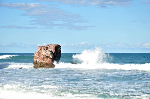Небольшие волны плещутся на скалах в синем море — стоковое фото