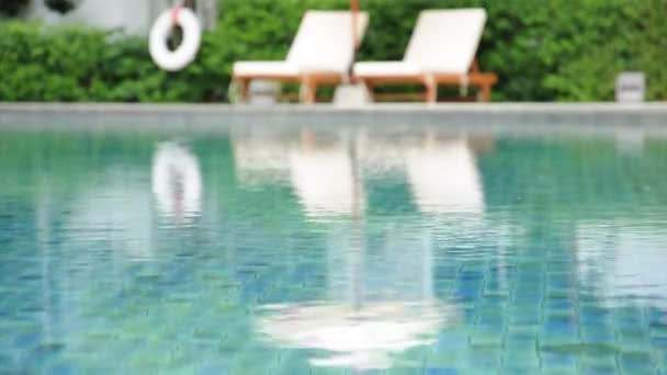 Eau ondulée dans la piscine avec chaises de plage et fond végétal vert 