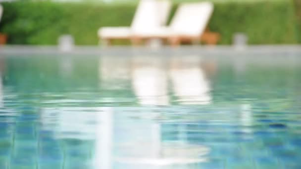 Agua ondulada en la piscina con sillas de playa y fondo de planta verde — Vídeos de Stock