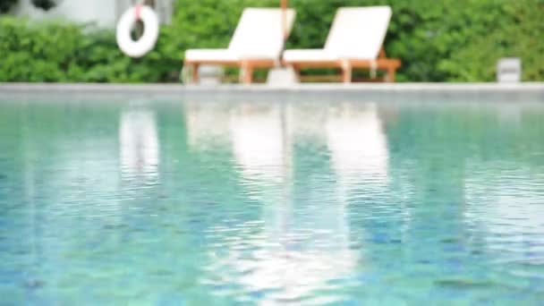 Eau ondulée dans la piscine avec chaises de plage et fond végétal vert 