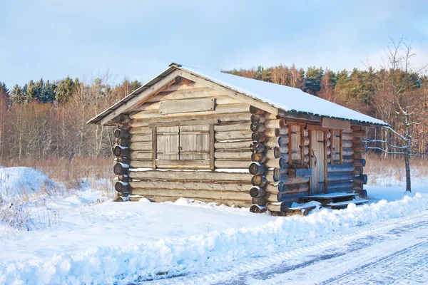 Náklady na dřevěný dům v zimě lesa. — Stock fotografie