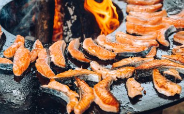 Grilling fish on a round grill with an open fire.