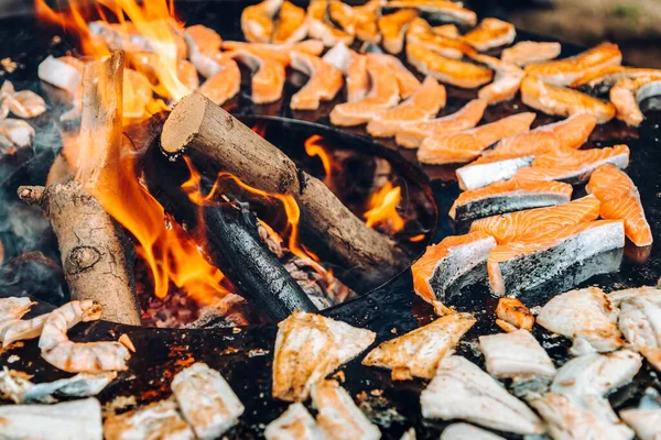 Grilling fish on a round grill with an open fire.