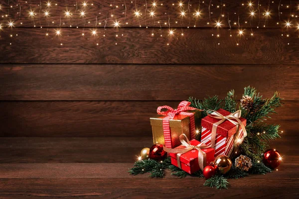 Mutlu Noeller ve mutlu yıllar. Hediyelerle dolu kutular, Noel oyuncakları ve tahta bir arka planda köknar dalları