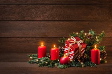 Mutlu Noeller! Bir hediye kutusu, dört mum ve ahşap bir arka planda köknar dalı.