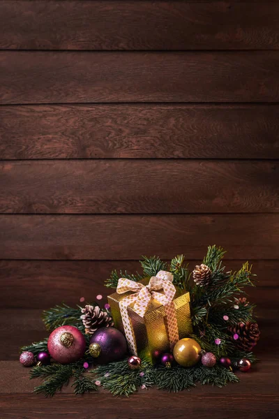 Merry Christmas! Box with a gift, Christmas balls and fir branches on a wooden background