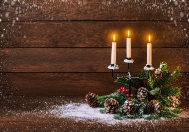 Mutlu Noeller ve mutlu yıllar. Mumlar, koniler ve köknar dallarıyla ahşap bir arka planda şamdan.