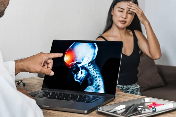 Doctor showing a x-ray of pain in the brain. Woman patient holding her head. Migraine Headache concept. High quality photo