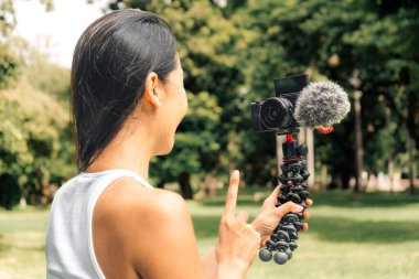 Young asian woman recording video with a camera for vlog and social media in a park. High quality photo