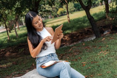 Happy woman writing and using a notebook in a park. High quality photo