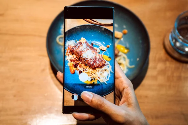 Close up of hand of a woman taking a photo of food with mobile phone. Sharing on social media. High quality photo