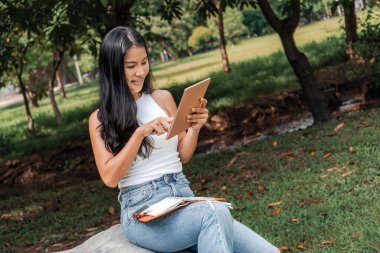 Happy woman writing and using a notebook in a park. High quality photo