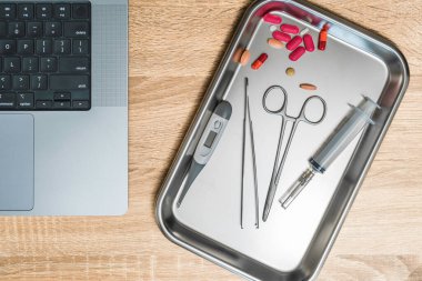 Top view of medical instruments and laptop. Syringe, clamp, thermometer on a clay. High quality photo