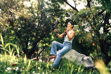 Young asian woman recording video with a camera for vlog and social media in a park. High quality photo
